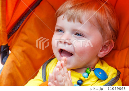 Funny toddler boy smiling outdoor in orange stroller Funny toddler boy smiling outdoor in orange stroller 11059063
