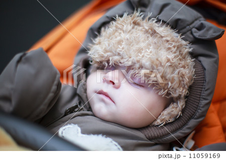 Adorable baby boy in winter clothes sleeping in stroller Adorable baby boy in winter clothes sleeping in stroller 11059169