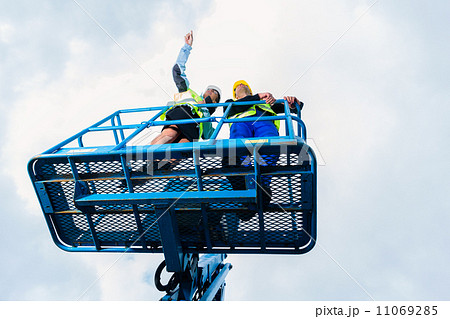 Construction workers on site in hydraulic lifting ramp 11069285