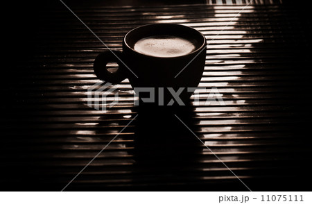 Cup of black coffee on the table in the dark interior Cup of black coffee on the table in the dark interior 11075111