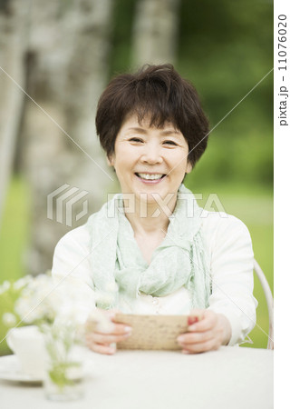 絵はがきを持ち微笑むシニア女性 11076020