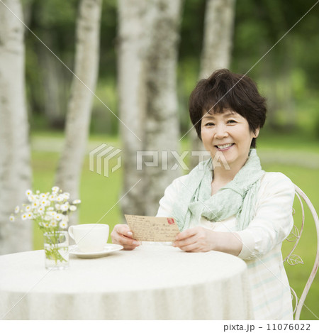 絵はがきを持ち微笑むシニア女性 11076022