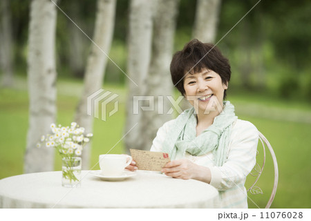 絵はがきを持ち微笑むシニア女性 11076028