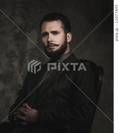 Handsome well-dressed with stick sitting in leather chair 11077845