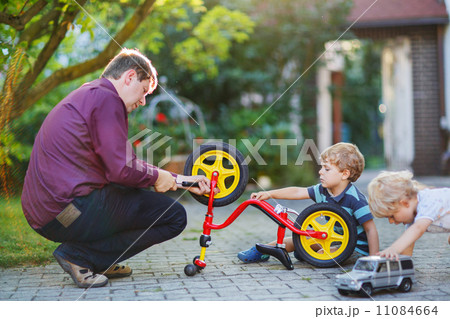 Two little sibling  boys repairing bicycle wheel with father 11084664