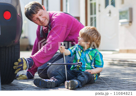 Father and adorable little boy repairing car and changing wheel 11084821