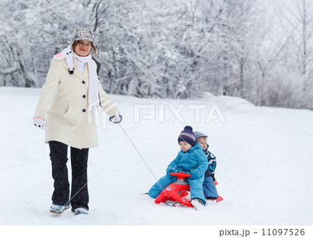 Two little siblings and their mother having fun on sledge on win 11097526