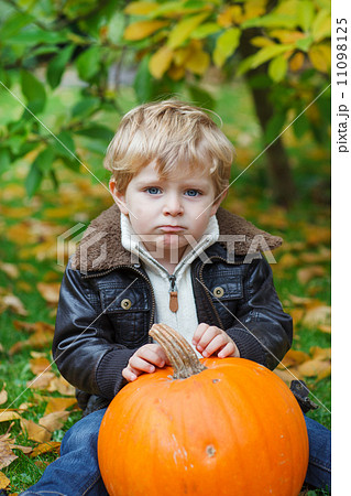 Little toddler with big orange pumpkin in garden 11098125