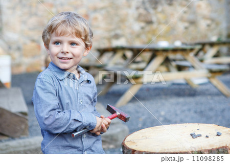 Little blond boy playing with hammer outdoors. 11098285