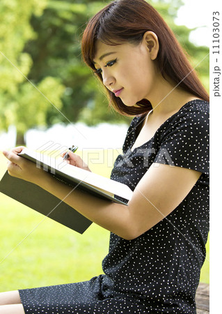 Beautiful young teenage female student reading in park Beautiful young teenage female student reading in park 11103073