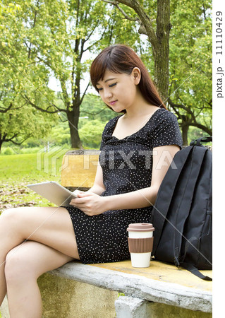 Beautiful student using tablet and drinking coffee in park Beautiful student using tablet and drinking coffee in park 11110429