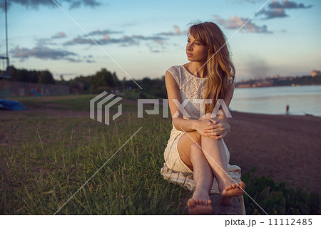 Young beauty smiling relaxing girl woman sitting near river or lake in nature outdoors portrait. Sof 11112485