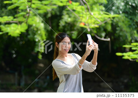 Asian girl selfie herself with mobile phone in park 11135375