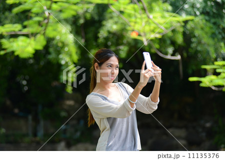 Asian girl selfie herself with mobile phone in park 11135376