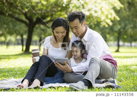 Happy Chinese family sitting on grass at the park using digital 11143556