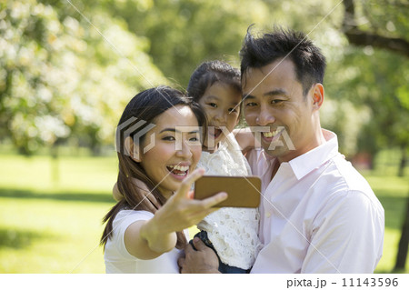 Happy Asian family taking selfies with there smartphone in the p Happy Asian family taking selfies with there smartphone in the p 11143596