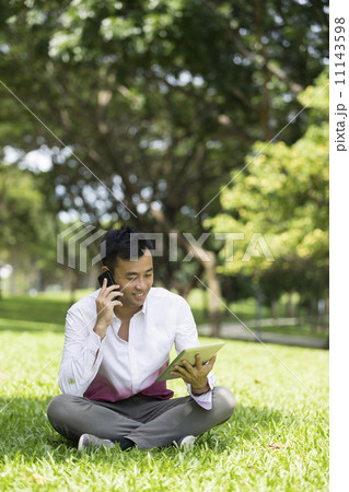 Chinese man using a Digital Tablet in city park. 11143598