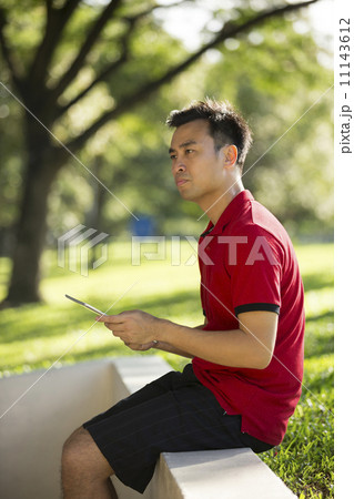 Chinese man using a Digital Tablet in city park. Chinese man using a Digital Tablet in city park. 11143612