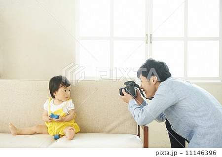 ソファで遊ぶ子供と写真を撮るお父さん 11146396