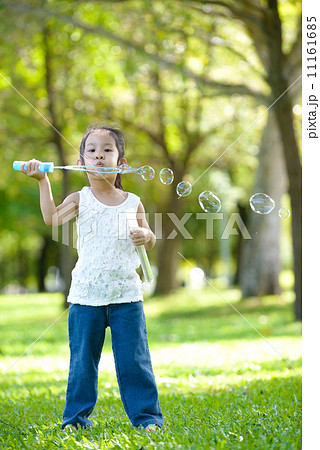 Little girl in causal blowing bubbles in a park Little girl in causal blowing bubbles in a park 11161685