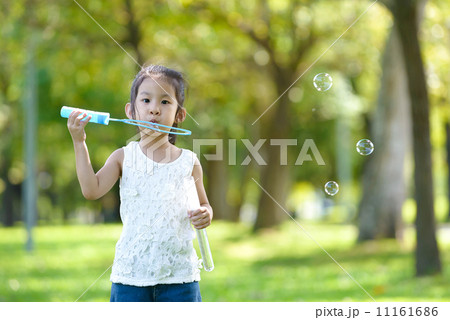 Little girl in causal blowing bubbles in a park 11161686