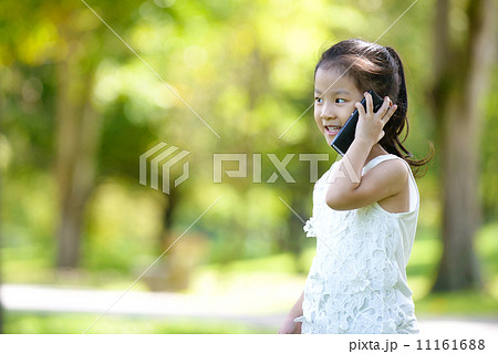 Little girl in causal using mobile smart phone in a park Little girl in causal using mobile smart phone in a park 11161688