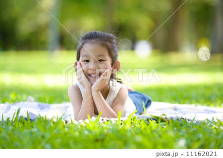 Cute little girl in casual laying on a mat in a park looking at camera 11162021