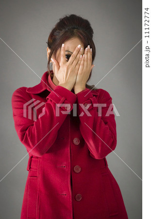 Shy Indian young woman peeking through covered face isolated on colored background 11172774