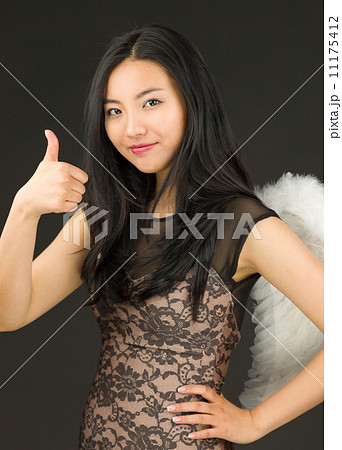Asian young woman dressed up as an angel with showing thumb up sign Asian young woman dressed up as an angel with showing thumb up sign 11175412