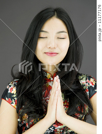 Asian young woman praying with her hands clasped Asian young woman praying with her hands clasped 11177176