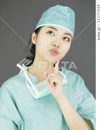 Asian female surgeon looking up with finger on chin isolated on colored background Asian female surgeon looking up with finger on chin isolated on colored background 11177434