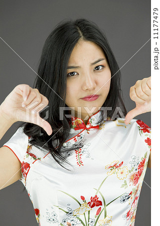 Unhappy Asian young woman giving thumbs down gesture 11177479