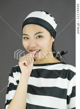 Young Asian woman smiling in prisoners uniform with finger in mouth Young Asian woman smiling in prisoners uniform with finger in mouth 11178440