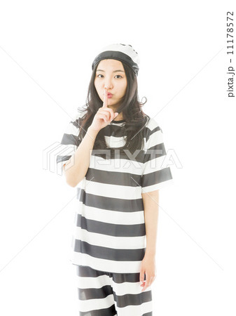 Young Asian woman standing with finger on lips in prisoners uniform Young Asian woman standing with finger on lips in prisoners uniform 11178572