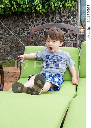 Boy sitting on a lounge chair and yawning Boy sitting on a lounge chair and yawning 11179563