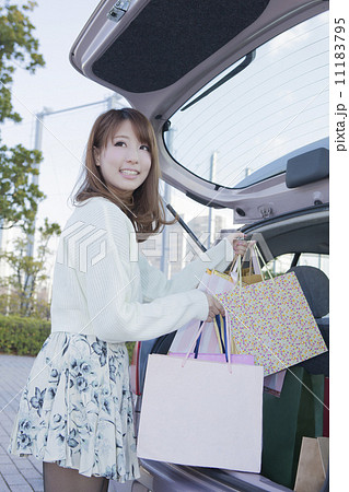 車のトランクにショッピングバッグを積む女性 11183795