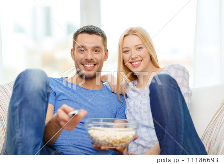 smiling couple with popcorn watching movie at home smiling couple with popcorn watching movie at home 11186693