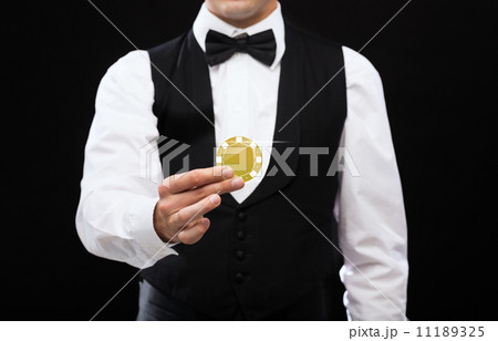 dealer holding golden poker chip dealer holding golden poker chip 11189325