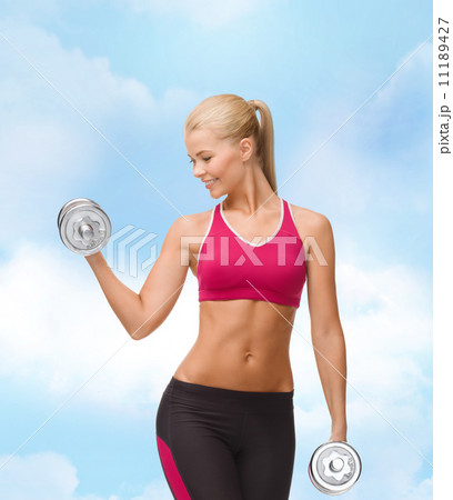 smiling woman lifting steel dumbbell smiling woman lifting steel dumbbell 11189427