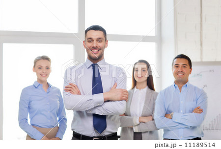 smiling businessman in office with team on back smiling businessman in office with team on back 11189514