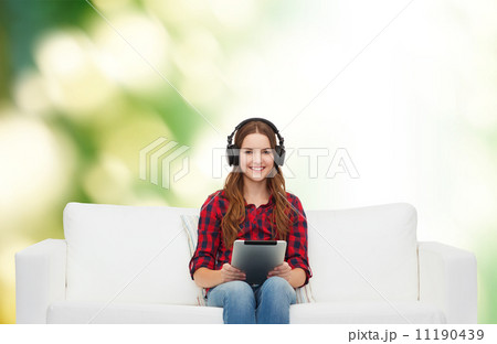 girl sitting on sofa with headphones and tablet pc girl sitting on sofa with headphones and tablet pc 11190439