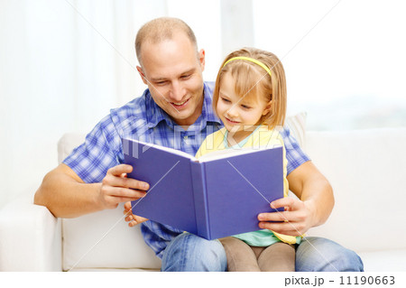 smiling father and daughter with book at home 11190663