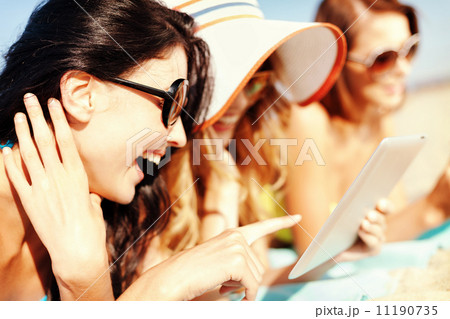 girls with tablet pc on the beach 11190735