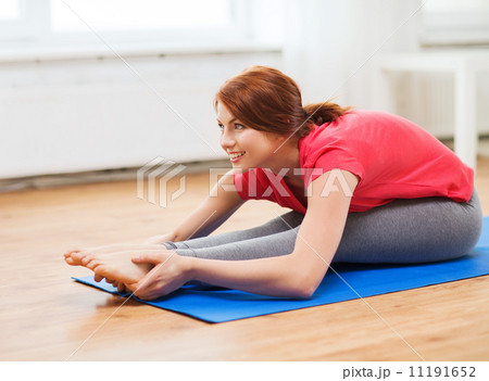 smiling teenage girl streching on floor at home smiling teenage girl streching on floor at home 11191652