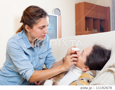 Adult daughter dripping eye drops to mother Adult daughter dripping eye drops to mother 11192676