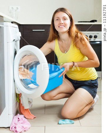 Smiling long-haired woman using washing machine Smiling long-haired woman using washing machine 11192701