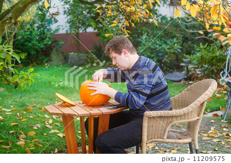 Young man making halloween pumpkin 11209575