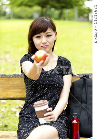 Beautiful girl holding apple and coffee in park Beautiful girl holding apple and coffee in park 11213621
