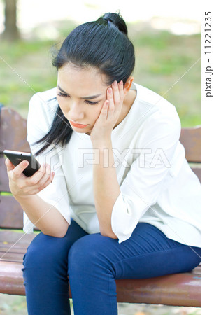 Unhappy young woman looking at smartphone 11221235