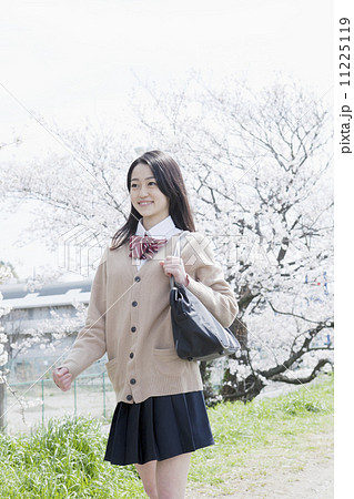 桜を背景に笑顔の女子高生の写真素材